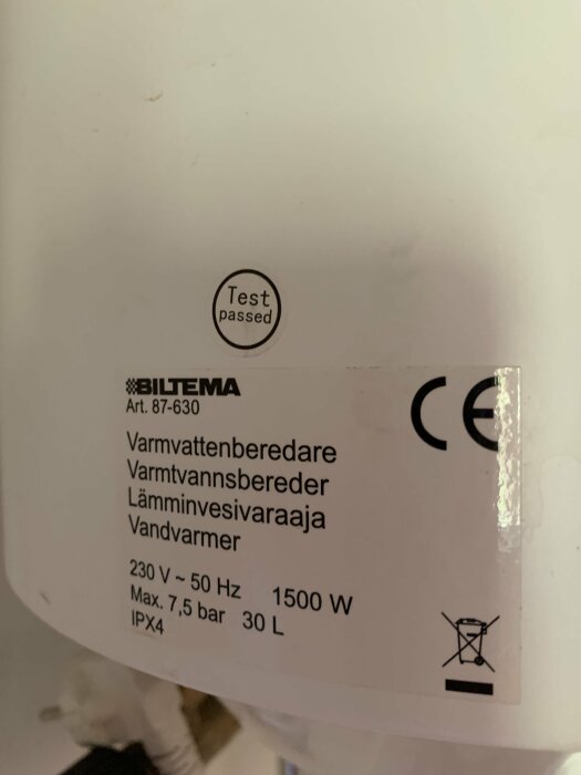 Närbild av en varmvattenberedare från Biltema med specifikationer: 230 V, 50 Hz, 1500 W, Max. 7,5 bar, 30 L, IPX4, och en godkänd testmärkning.