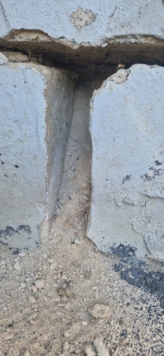Närbild på spruckna betongblock med synlig jord och smuts mellan blocken.