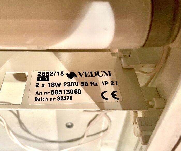 Närbild på en etikett inuti ett badrumsskåp som visar specifikationer för belysningen, inklusive texten "VEDUM, 2 x 18W 230V 50Hz, Art.nr: 58513060".