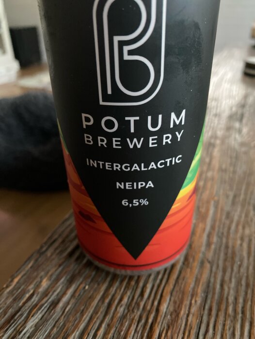 Burk med Potum Brewery Intergalactic NEIPA, 6,5% alkohol, på ett träbord.