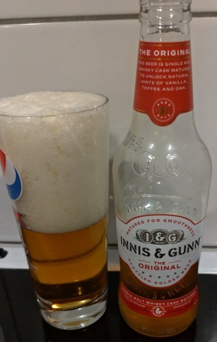 Innis & Gunn Original ölflaska bredvid ett högt glas med skummande gyllene öl.