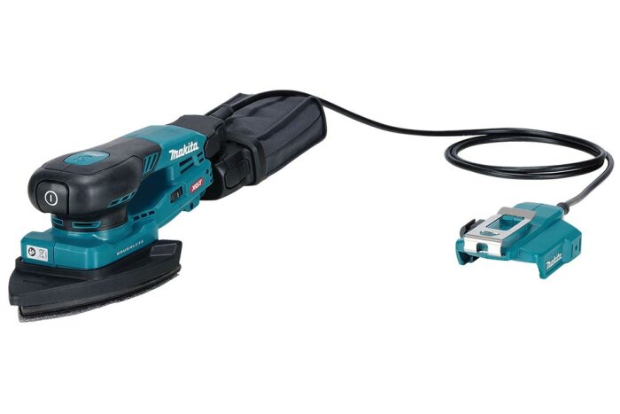 Makita multiverktyg tm001 med slipmaskinsfunktion och ansluten batteriladdare, placerat på vit bakgrund.