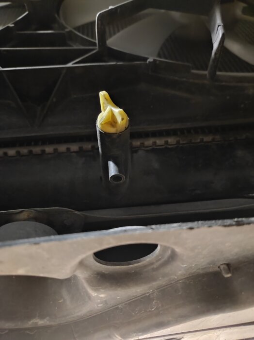 Närbild på oljekran och slanganslutning under en Lexus, omgivna av mörk plast.