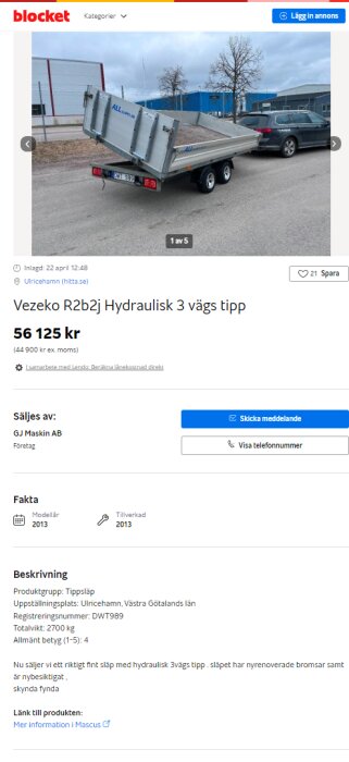 Bild av en Vezeko R2b2j hydraulisk tippvagn, trevägstipp, stående parkerad på en asfalterad yta bredvid en grå bil med byggnader i bakgrunden.