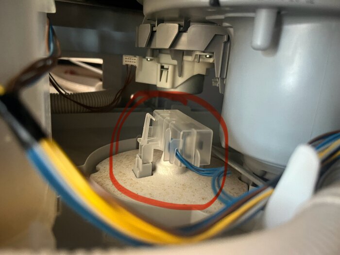 Närbild på en Siemens-diskmaskins inre komponenter med blåa kablar och en komponent som är markerad med en röd cirkel, sannolikt Aquastop-ventilen.