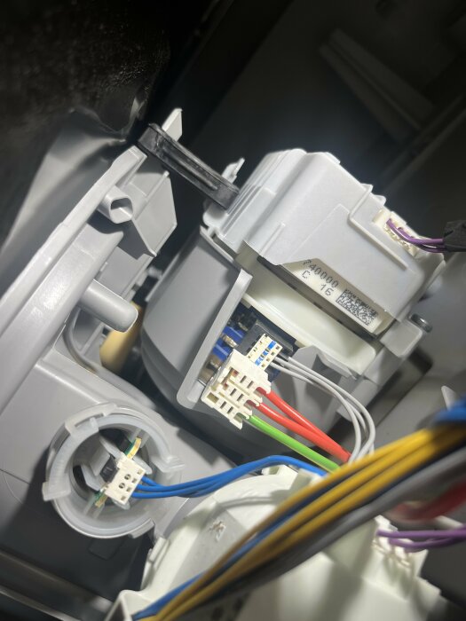 Närbild av en öppen Siemens-diskmaskin där olika färgade kablar är anslutna till en komponent, möjligen Aquastop-ventilen, och en annan komponent finns nedre vänster.