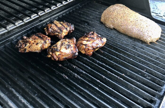 Kycklinglår och flankstek grillas på en grill.