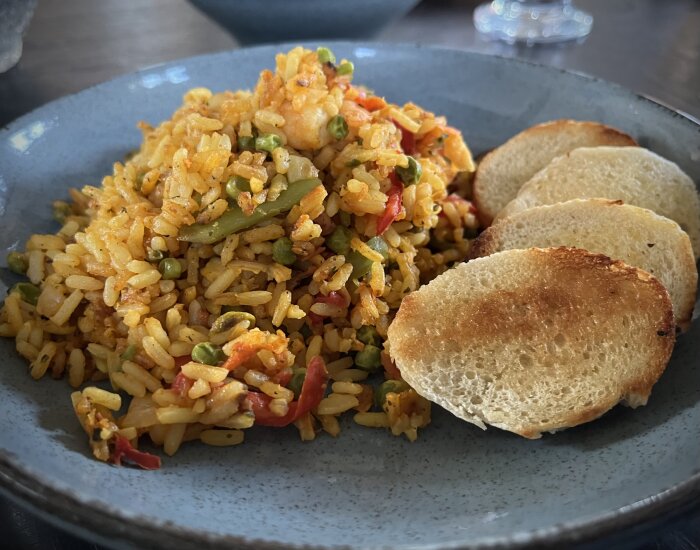 Tallerk med färdigfrusen Paella från Lidl, serverad med grillat bröd vid sidan av.