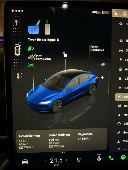 Bilden visar bilens digitala display som visar kördata, laddningsstatus och illustration av en blå bil. Texten säger att bilen har kört 525 km och har 8% batteri kvar.