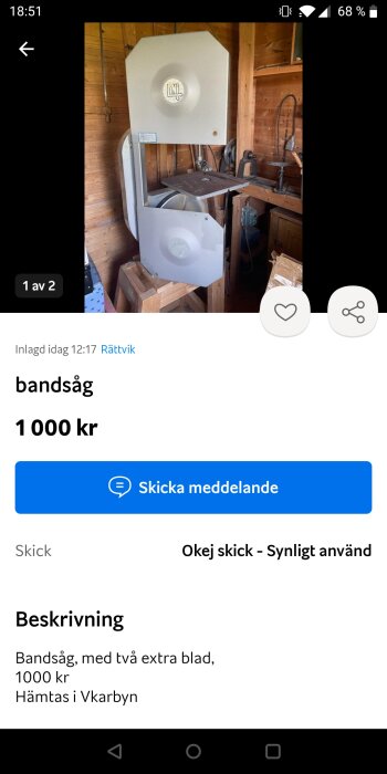 Bandsåg i ett träverkstad, med ett metallbord och en trästödstruktur. Maskinen är märkt med "UNI".