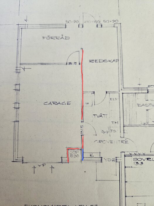 Ritning av garage med markerade väggar kring sopskåpet. En röd linje visar den bärande väggen, medan en blå linje markerar en vägg som ser tunnare ut ovanför sopskåpet.