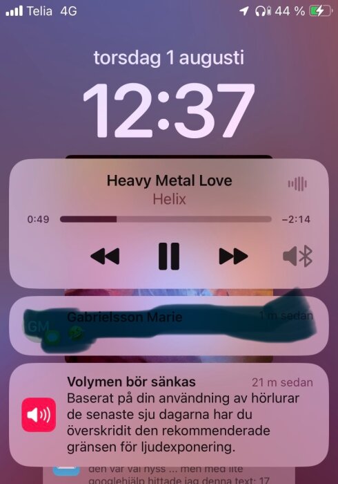 En telefon visar klockan 12:37 torsdagen 1 augusti. En låt "Heavy Metal Love" av Helix spelas. En volymvarning syns: "Volymen bör sänkas", baserat på hörlursanvändning.