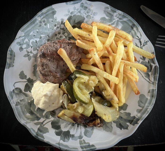 Tallrik med grillad oxfilé, pommes frites, ugnsstekta grönsaker och en klick bearnaisesås.