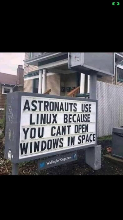 En skylt utanför ett hus med texten: "Astronauts use Linux because you can't open Windows in space.