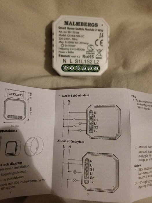 Malmbergs smarta hem-switchmodul bredvid en instruktionsmanual som visar kopplingsdiagram för en enhet med och utan strömbrytare.