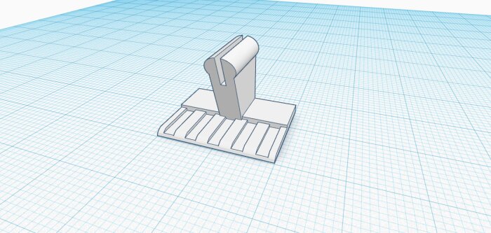 3D-modell av ett spröjsbeslag ritat i Tinkercad, med rutnät i bakgrunden. Detaljerad design för 3D-utskrift.