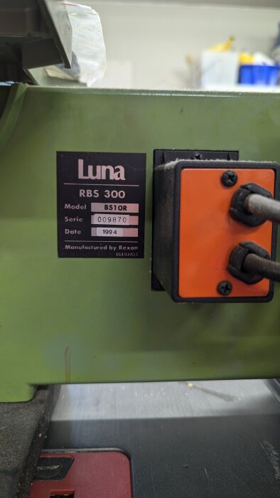 Industrimiljöbild visar nära utsikt över Luna RBS 300 med modellnummer BS10R och serienummer 009870. Tillverkningsår 1994. Märkning bredvid orange knappsats.