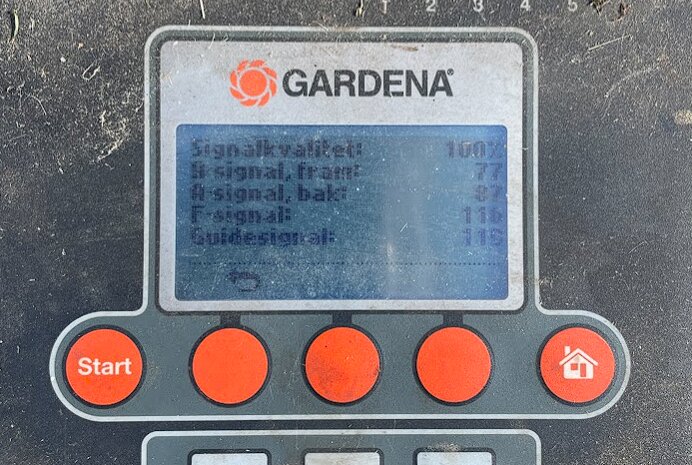 Närbild av en display på en Gardena-robotgräsklippare som visar signalstatus och andra inställningar bredvid fyra oranga knappar.