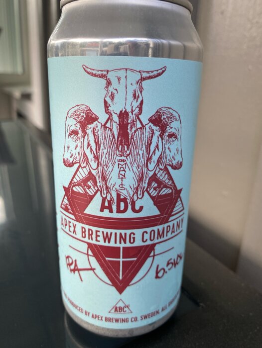 Aluminiumburk med etikett i ljusblått och rött från Apex Brewing Company, med illustration av en djurskalle och fårhuvuden samt texten "ABC 6.5%" och logotyp.