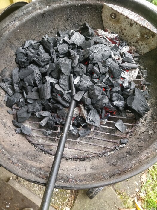 Glödande kol i en kolgrill med en tång på grillgallret.