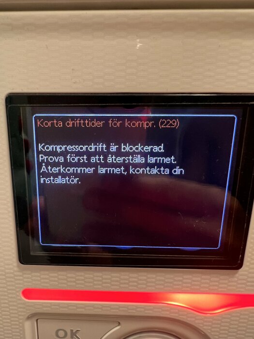 Närbild på displayen av en Nibe 370 med felmeddelandet "Korta drifttider för kompr. (229). Kompressordrift är blockerad. Prova först att återställa larmet.