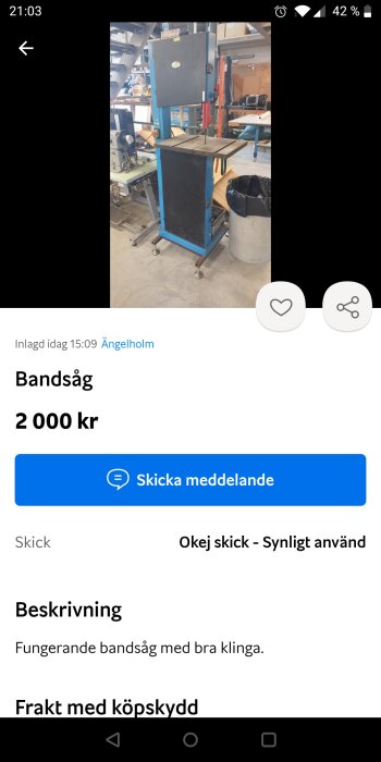 Bild på en bandsåg med blå ram och svart frontpanel, placerad i vad som ser ut som en verkstad. Bandsågen annonseras för 2000 kr och är i okej skick.