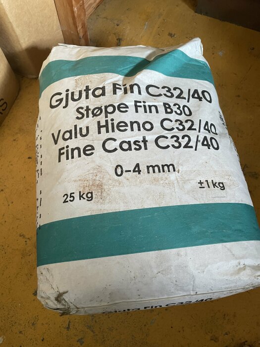 En 25 kg säck med fin gjutcement C32/40 placerad på ett golv.