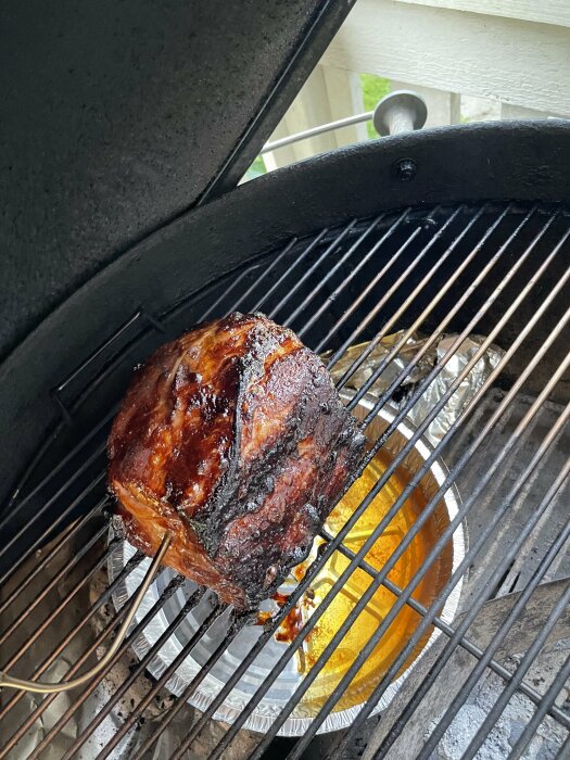 Grillat kött på en kolgrill med en aluminiumform med saft under, klar att avnjutas efter en lång dag av byggarbete.