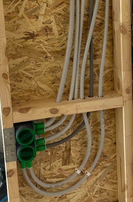 Elektriska slangar och kopplingsdosor installerade i en väggkonstruktion av trä och plywood.