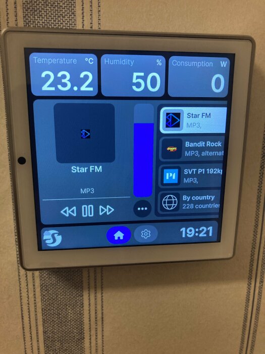 Wall display visar en väderprognos med temperatur 23,2°C och luftfuktighet 50%, samt spelar radiostationen Star FM. Klockan visar 19:21.