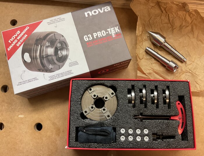 Nova G3 PRO-TEK chuck set med tillbehör i en låda. Verktygen är packade i skum med en röd T-handtag nyckel, samt extra backar och bultar.