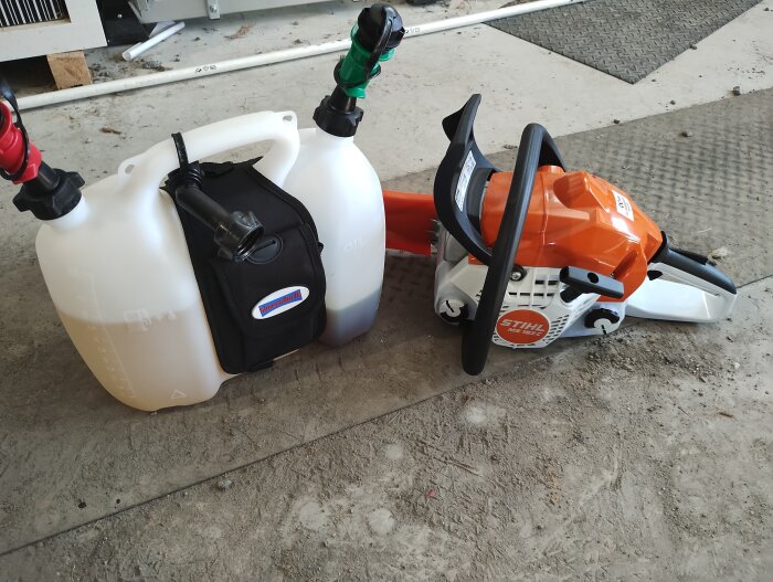 Ny Stihl motorsåg och en tankdunk med två separata fack för bensin och olja, placerade på ett golv i ett garage.