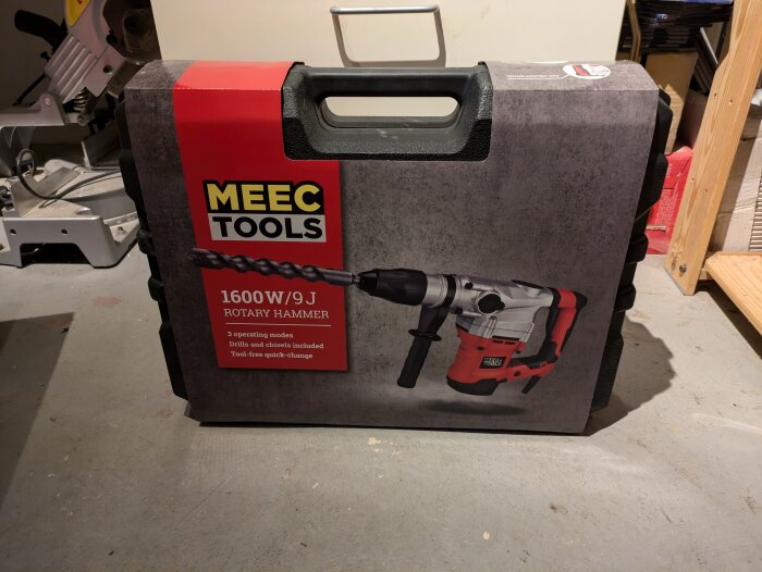 En MEEC TOOLS-borrhammare på 1600W/9J i ett svart fodral med röd etikett, placerad på ett golv i ett garage eller verkstad.