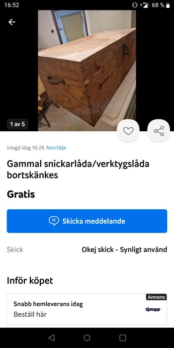 Gammal snickarlåda eller verktygslåda av trä, med metallhandtag på sidan, står på ett bord i inomhusmiljö.