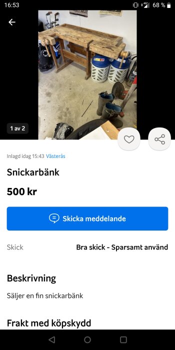 Begagnad snickarbänk i trä med skruvstycke, omgiven av verktyg och hinkar i en garage-liknande miljö.