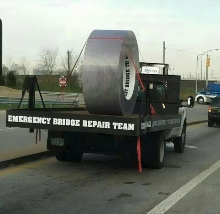 En lastbil med en jättelik rulle silvertejp på flaket och texten "Emergency Bridge Repair Team" på sidorna.