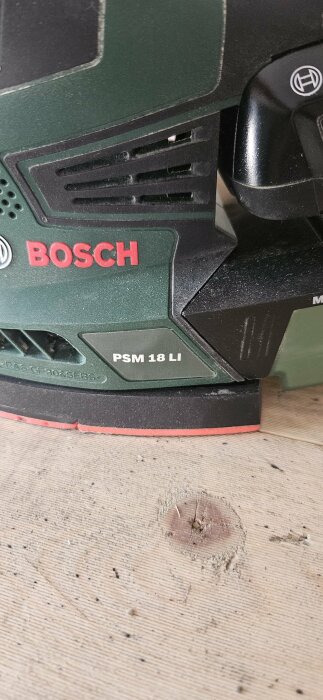 Grön Bosch PSM 18 LI slipmaskin på ljus trägolv.