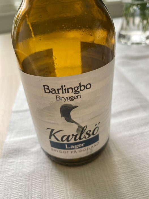 Flaska med "Karlsö Lager" öl från Barlingbo bryggeri, bryggd på Gotland, stående på en vit duk.