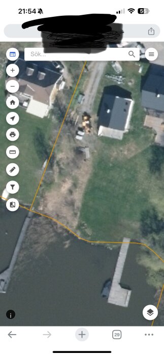 Satellitbild av en villatomt vid vattnet där en grannes brygga delvis ligger över tomtgränsen och sträcker sig in på mark tillhörande frågeställarens tomt.