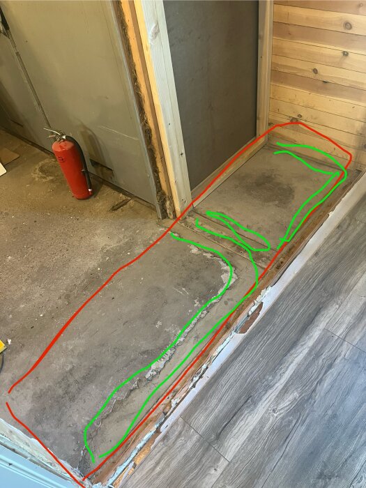 Bild av ett golv med betonglagade fåror markerade med gröna streck och ett område för flytspackling markerat med en röd rektangel, i ett rum under renovering.