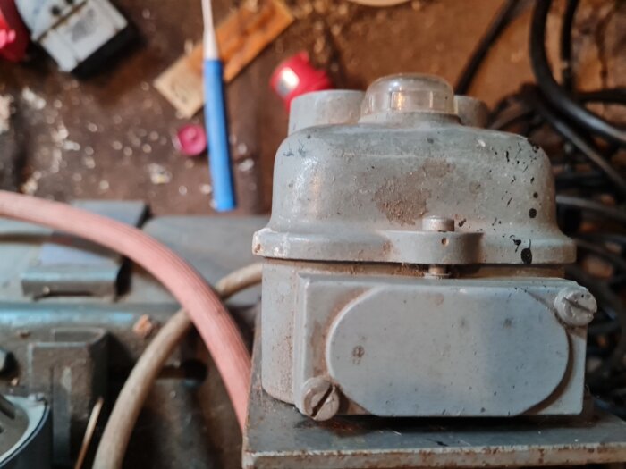 Närbild på en ASEA damd 6 motor, en del av en vintage kompressor utan traditionell tryckvakt, omgiven av arbetsverktyg och kablar.