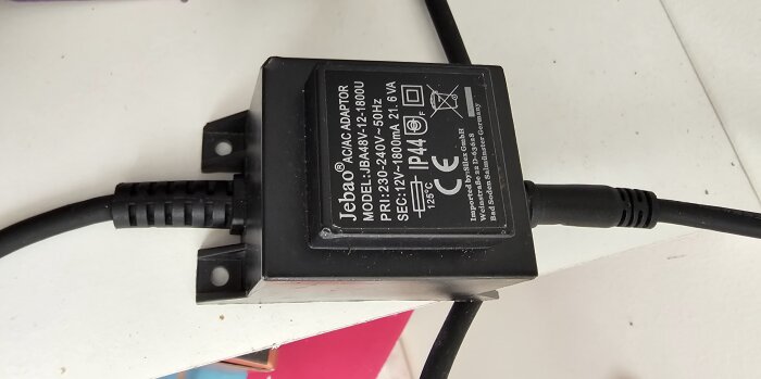 Bild på en Jebao AC/AC adapter modell JBA-48V-12-1800U med specifikationer och CE-märkning, placerad på ett vitt underlag.