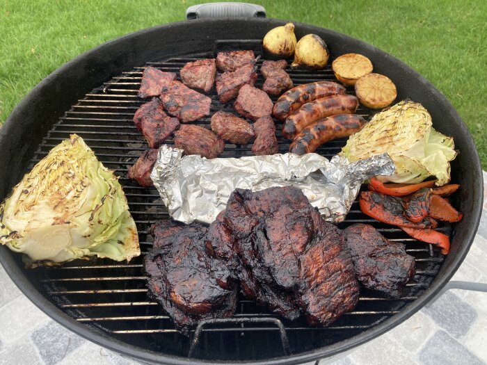 En grill fylld med olika köttbitar, korv, grillad kål, citronhalvor och paprika samt foliepaket på en lördag.