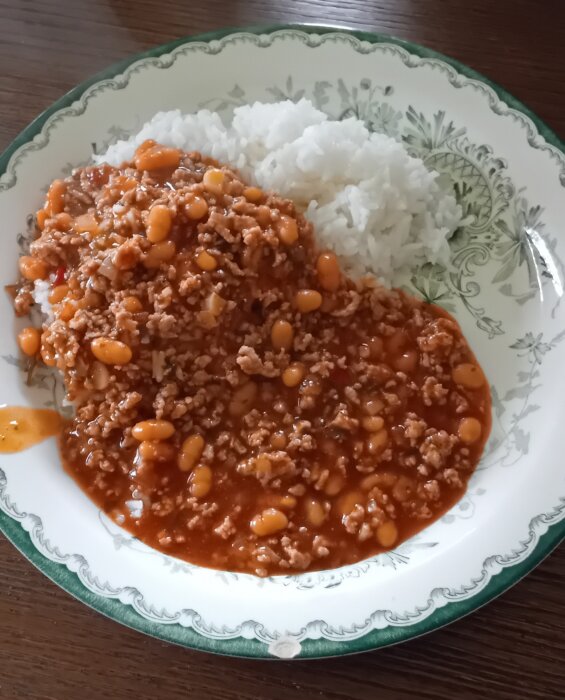 En tallrik med chili con carne och ris, serverad på en porslinstallrik med mönster.