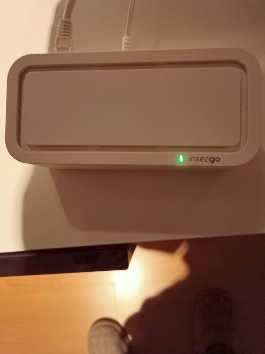 Modem från Inseego med grön blinkande lampa och anslutning till nätverk, placerad på en bänk med kablar anslutna.