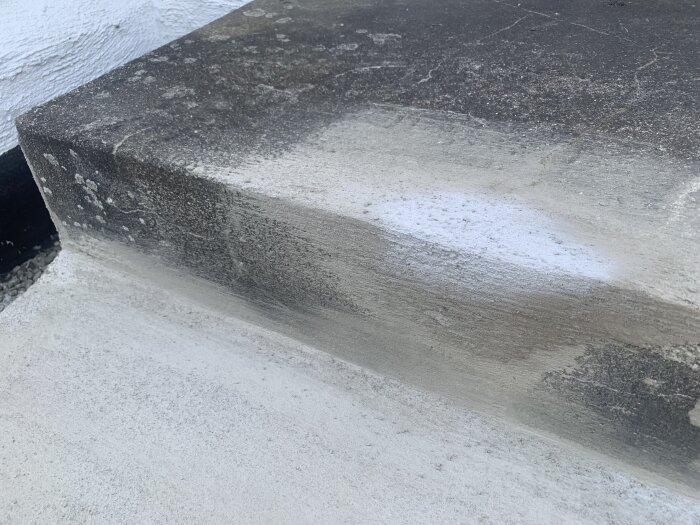 Närbild på en betongtrappa där en lagning gjord med A-bruk visar fläckar av nästan vit färg.