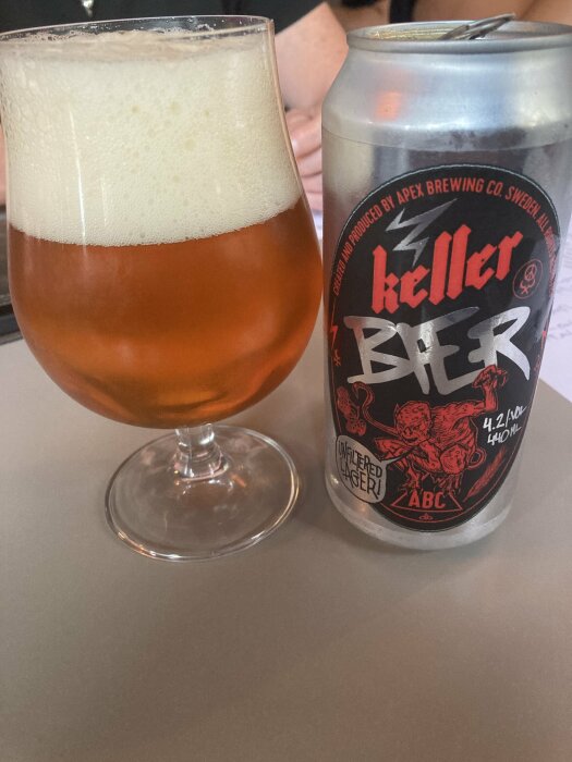 Ett glas med skummande öl och en burk Apex Keller Bier från Apex Brewing Co.