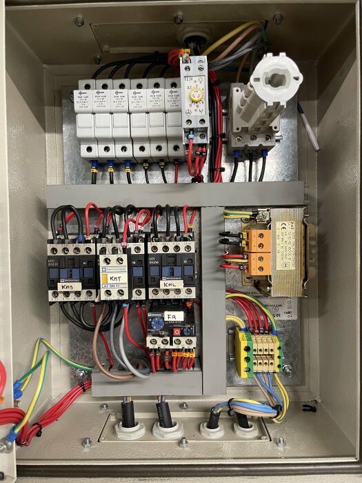 Elektriskt skåp med flera anslutna kablar, kontaktorer och kretsbrytare, varav en av är vittejpad och oinkopplad, samt en vit jordfelsbrytare (JFB).