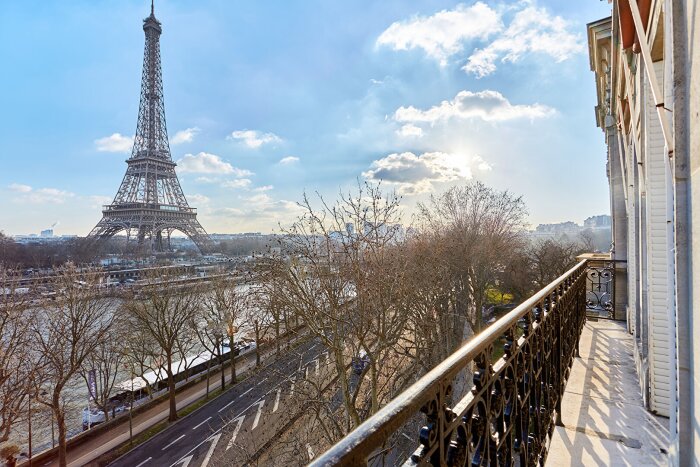 Balkong med utsikt mot Eiffeltornet vid Seine i Paris, en solig kväll.