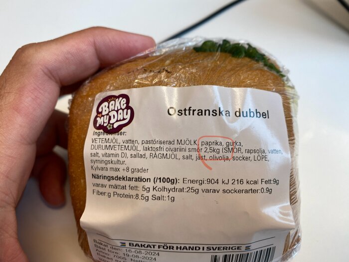 Etiketten på en plastförpackad ostfranska med varumärket "Bake My Day" och ingredienser listade som bland annat vetemjöl, pastöriserad mjölk och paprika.